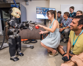 Photo of graduate students interacting with the iCub robot. 