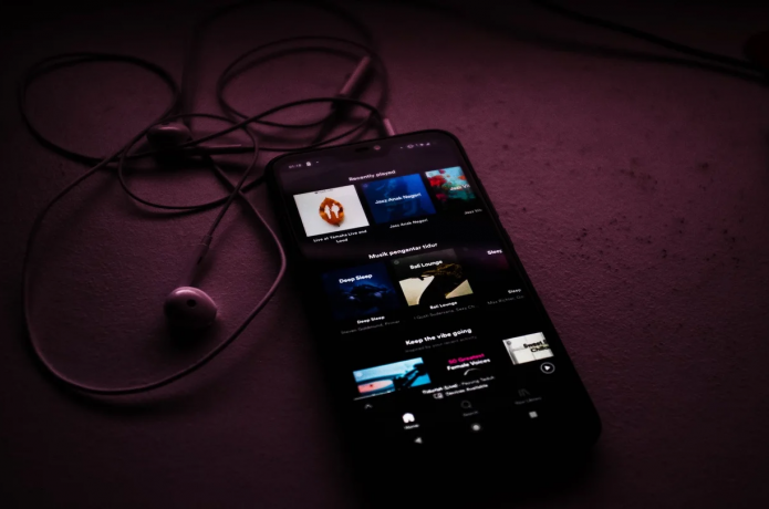 an iphone with a music app open and some headphones plugged into it.