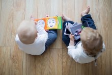two infants sitting reading books