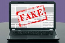 Image of a laptop displaying an article that has been stamped "Fake" 