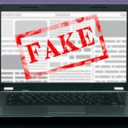 Image of a laptop displaying an article that has been stamped "Fake" 