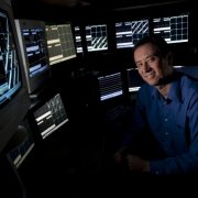Photo of Prof. Matt Wilson sitting in front of multiple computer displays. 